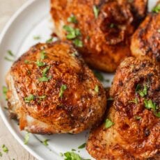 Four air fryer chicken things on a white plate garnished with freshly chopped parsley.