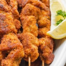 Breaded Chicken Skewers with lemon wedges served on platter