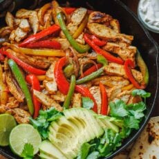 Chicken fajitas served in a skillet with avocado and cilantro