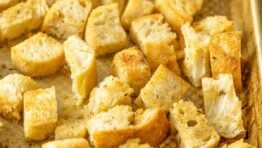 Homemade croutons on a metal baking sheet.