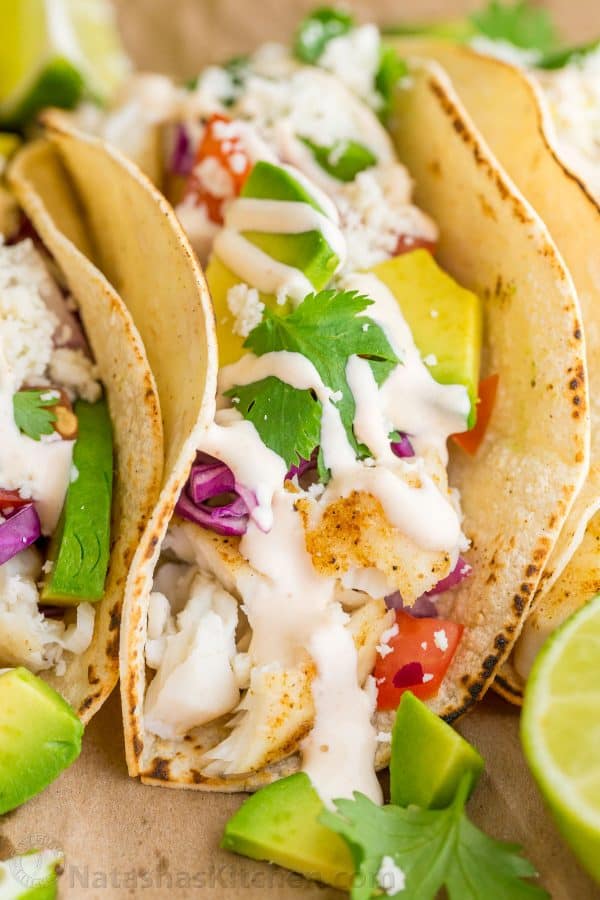 Our go-to fish tacos recipe for entertaining! Easy, excellent fish tacos with the best fish taco sauce; an irresistible lime crema! | natashaskitchen.com