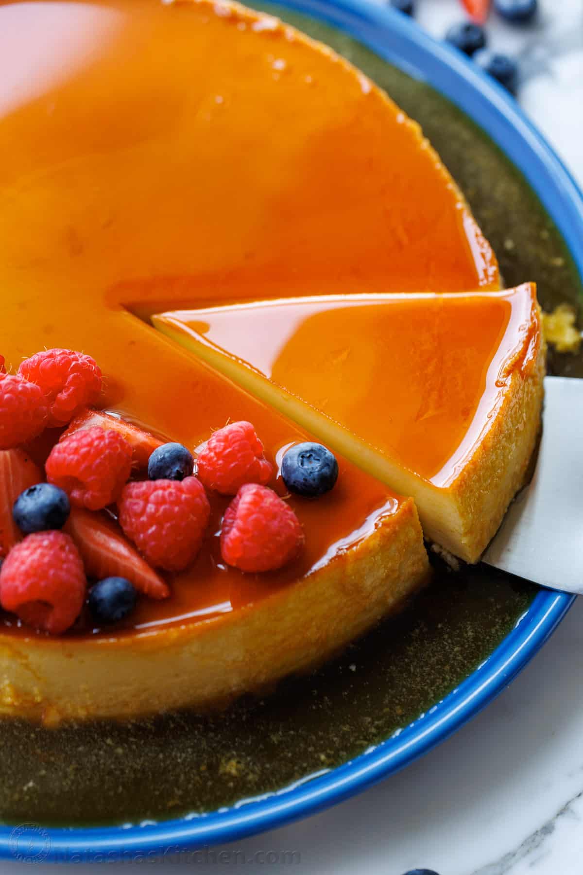 Flan dessert served on a cake platter with berries