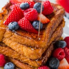 French toast slices stacked and served with berries and maple syrup