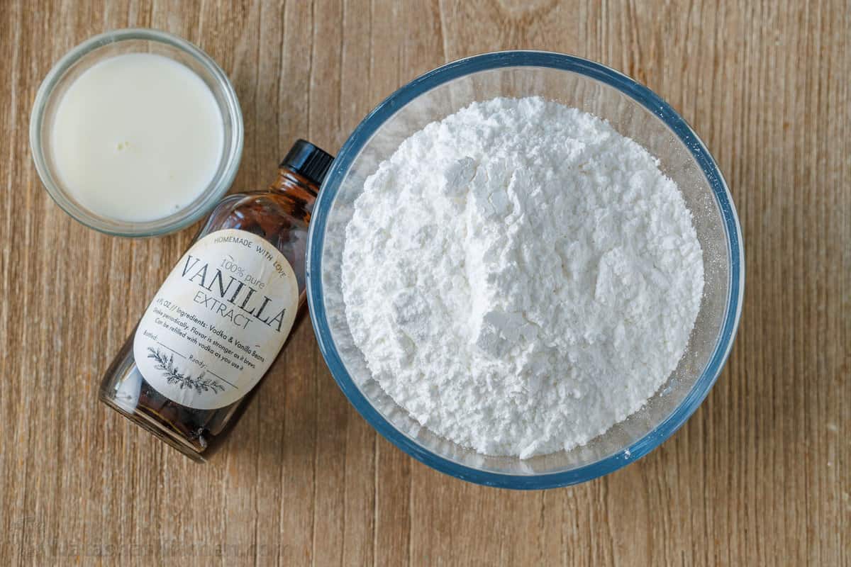 ingredients for cookie icing including powdered sugar, vanilla and milk