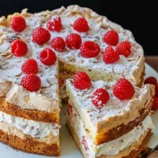 Himmelstorte layered with cake, whipped cream, and raspberries on a cake platter sliced to serve