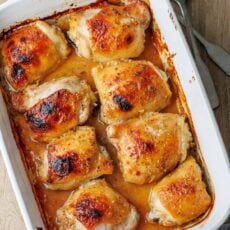 Overhead view of baked honey mustard chicken thighs in a ceramic casserole dish.