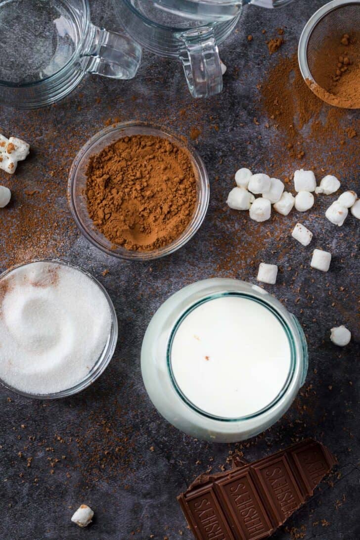 Hot chocolate ingredients on platter with sugar, milk and cocoa powder.