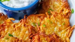 Latkes fried and topped with chives. On a plate with sour cream