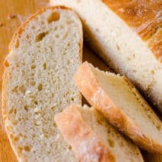 Artisan Bread slices on a cutting board with loaf of no-knead bread