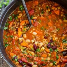 pasta e fagioli in soup pot with serving spoon garnished with basil