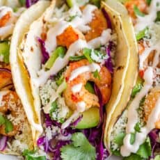 Shrimp taco up close on platter drizzled with sauce