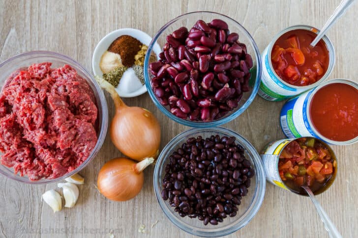 Ingredients for chili with ground beef, beans, tomatoes, onion and seasonings