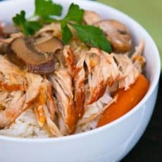 A bowl of slow cooker pulled pork in a mushroom sauce on top of rice