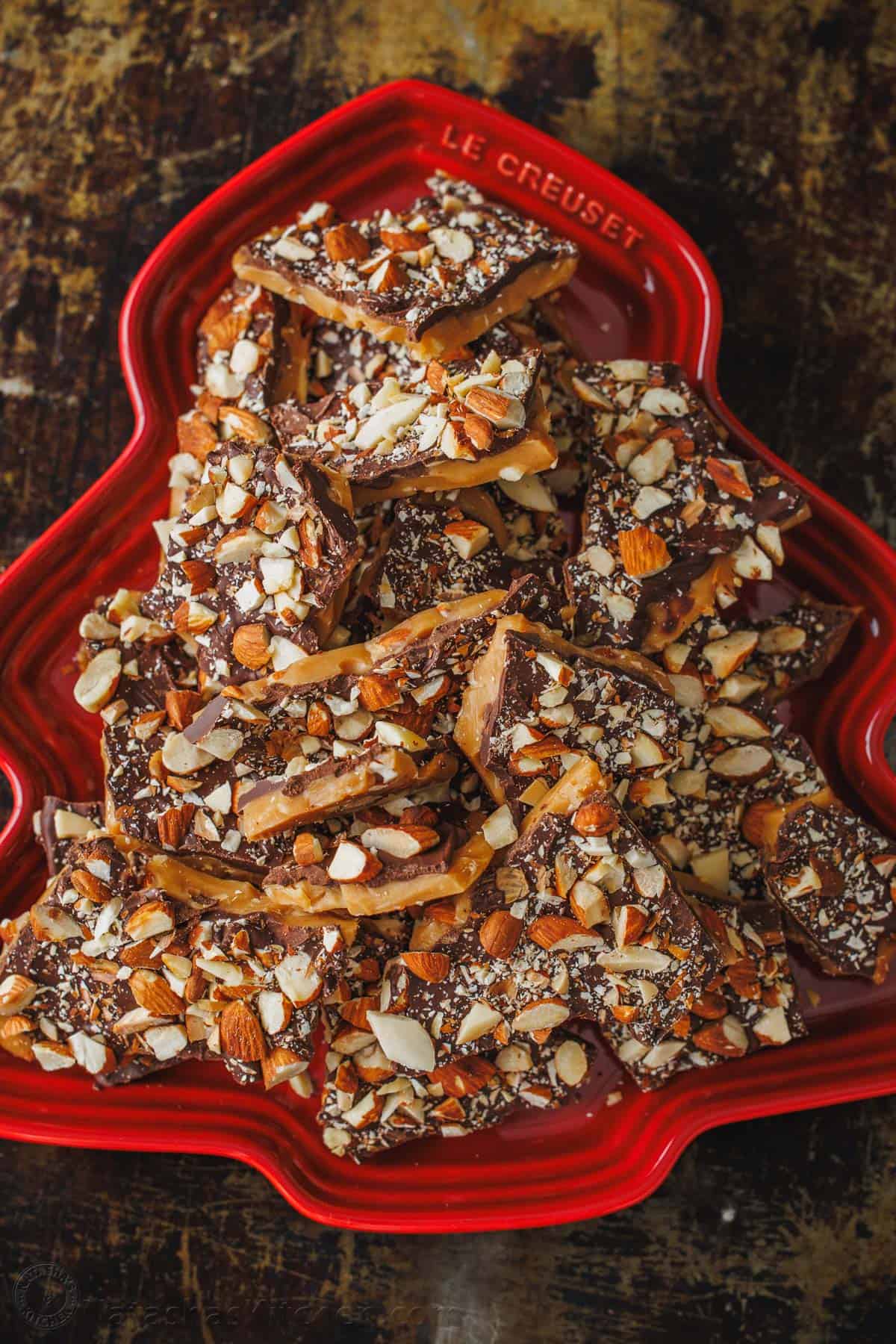 Chocolate and nuts layered with candy in a red holiday dish